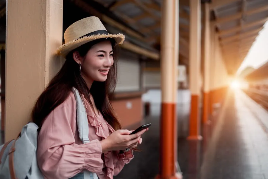A traveller checking her phone on a station platform